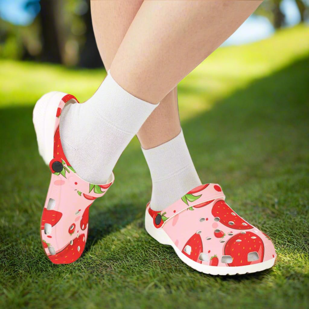 Pink sandals with strawberry pattern worn with white socks on a white background