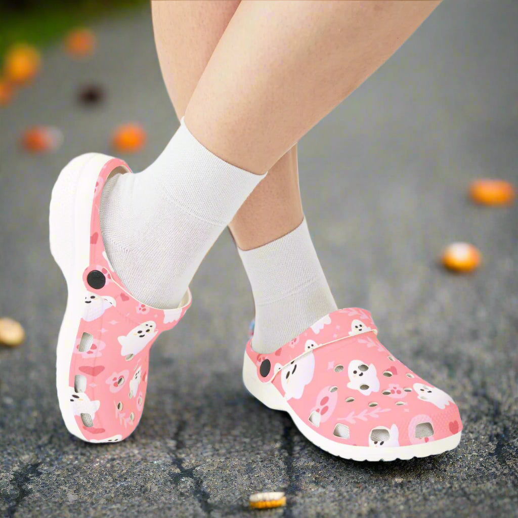Pink clogs with ghost design worn with white socks on a white background