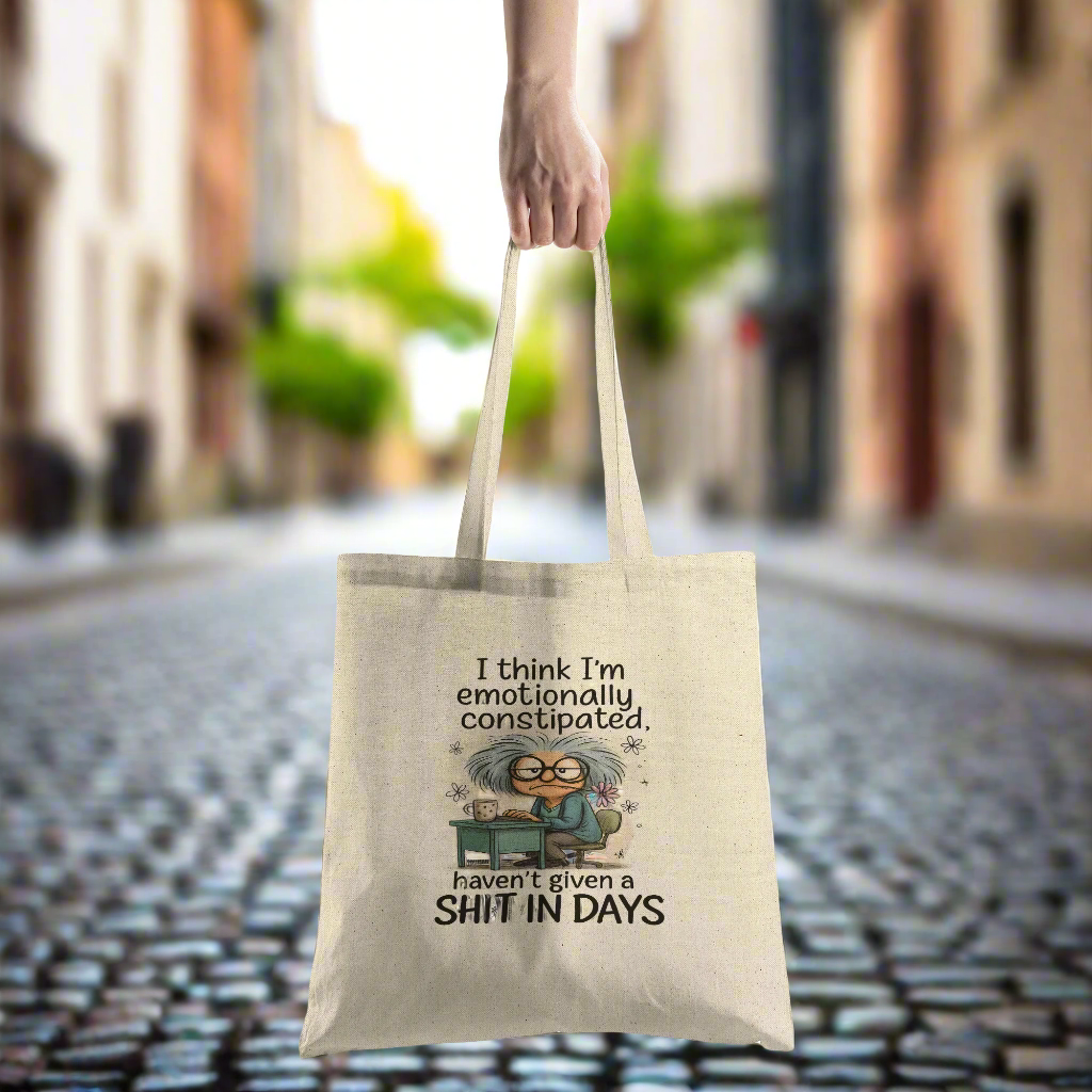 Tote bag with humorous design and text held by a hand on a white background