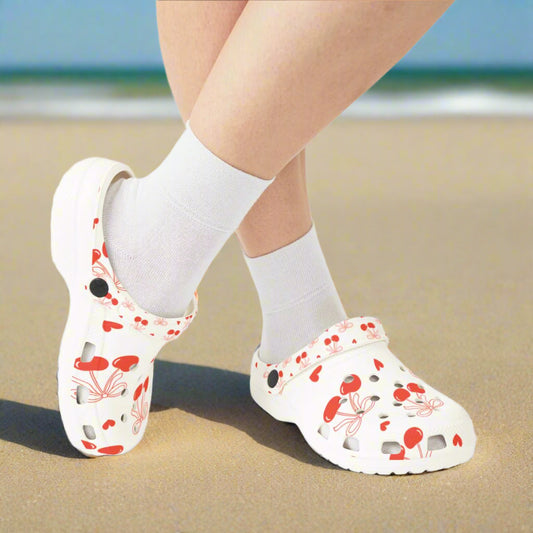 White clogs with red floral pattern worn with white socks on a white background