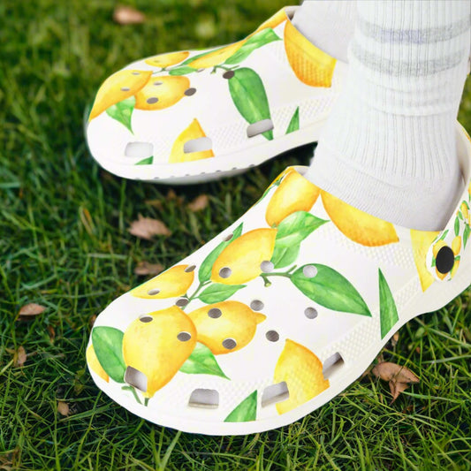 White clogs with lemon design worn by a person with white socks on a white background