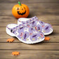 Pair of purple clogs with Halloween-themed design on a white background