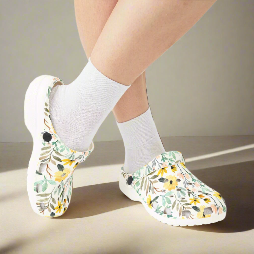 Floral-patterned clogs worn with white socks on a white background