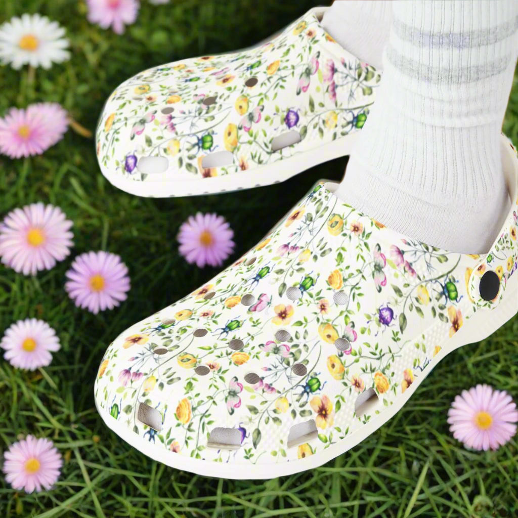 Floral-patterned clogs on feet with white socks against a white background