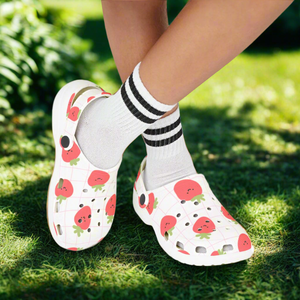 White clogs with watermelon pattern worn with striped socks on a white background