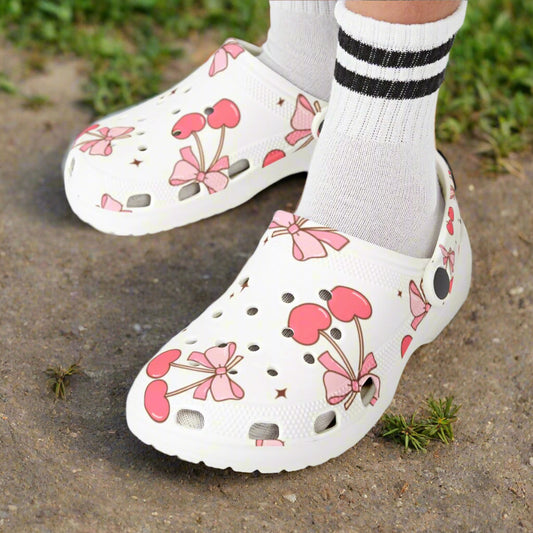 White clogs with pink floral design worn by a child on a white background